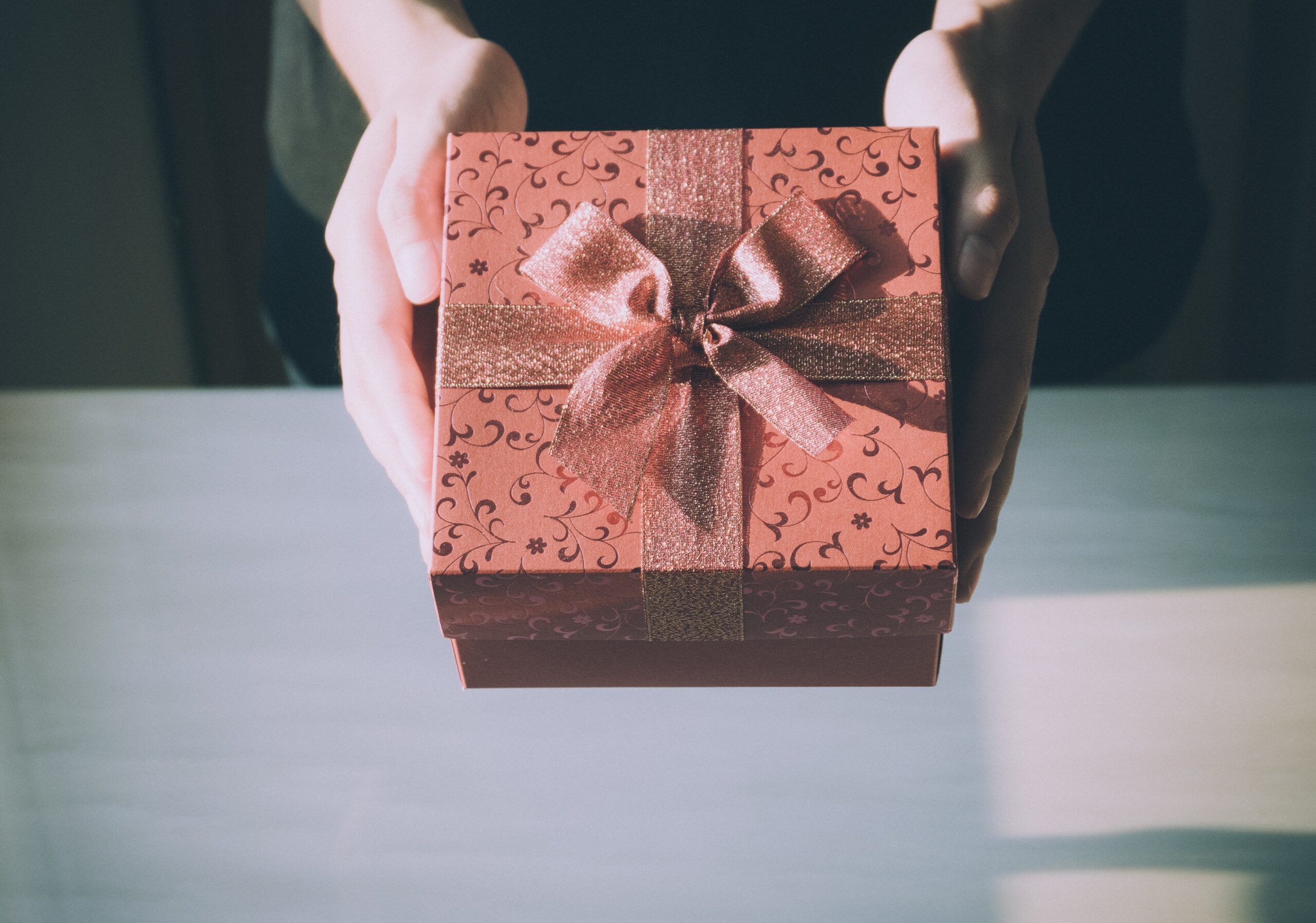 hands holding out gift box in pink